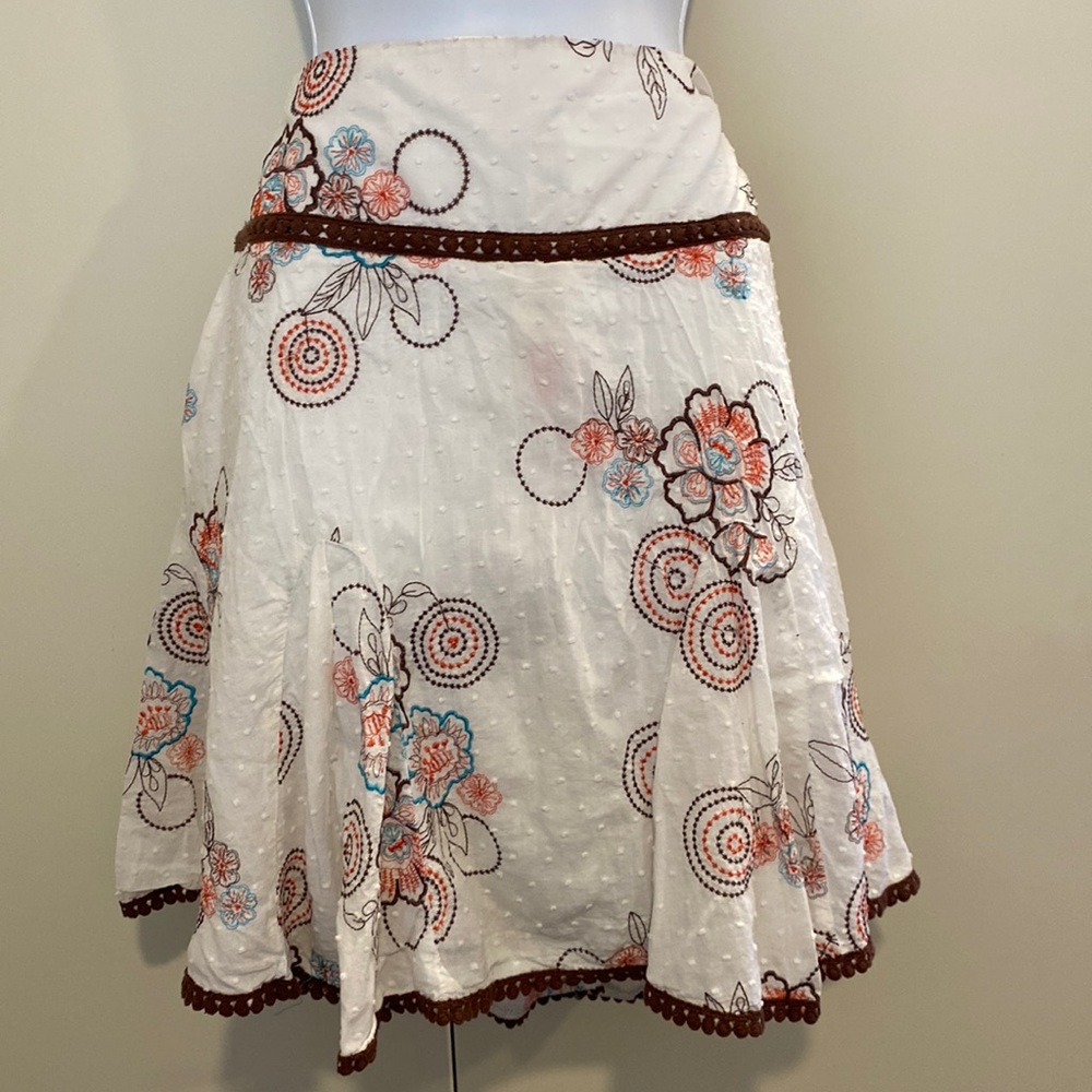White skirt with embroidered flowers and designs in brown orange and turquoise